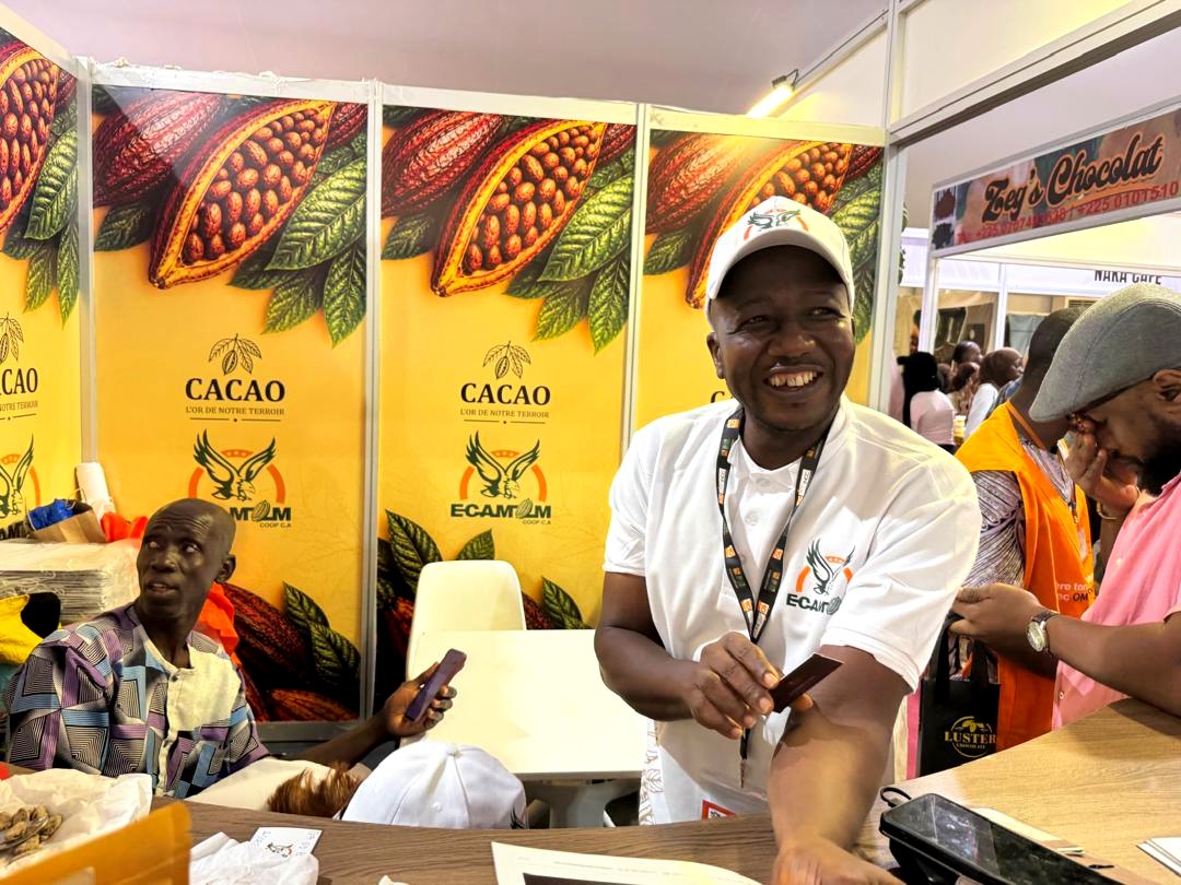 Cooperative representative welcoming visitors at a cocoa stand during JNCC 2026
